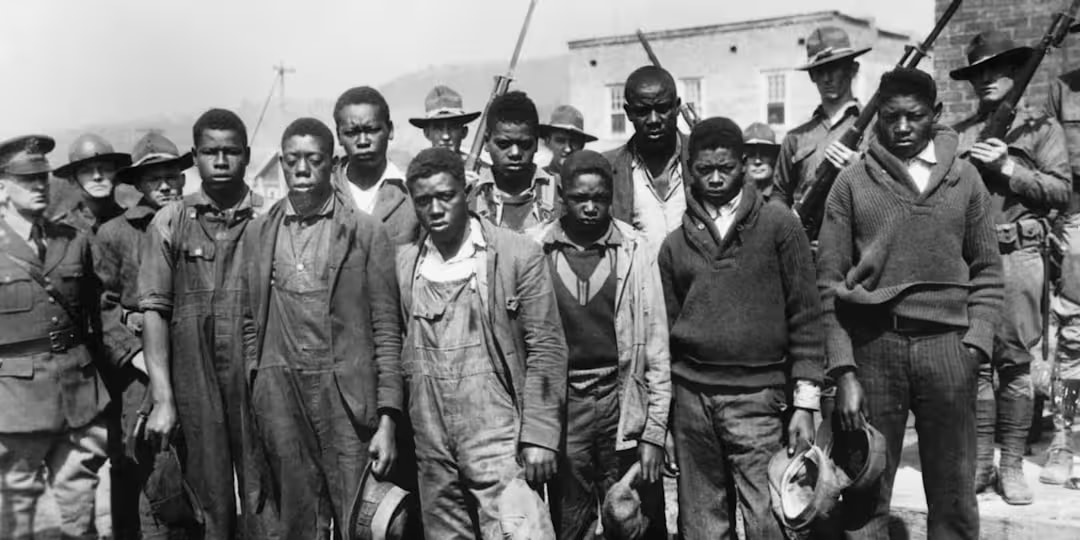 Nine young Black men, the Scottsboro Boys, standing under guard in Alabama in 1931